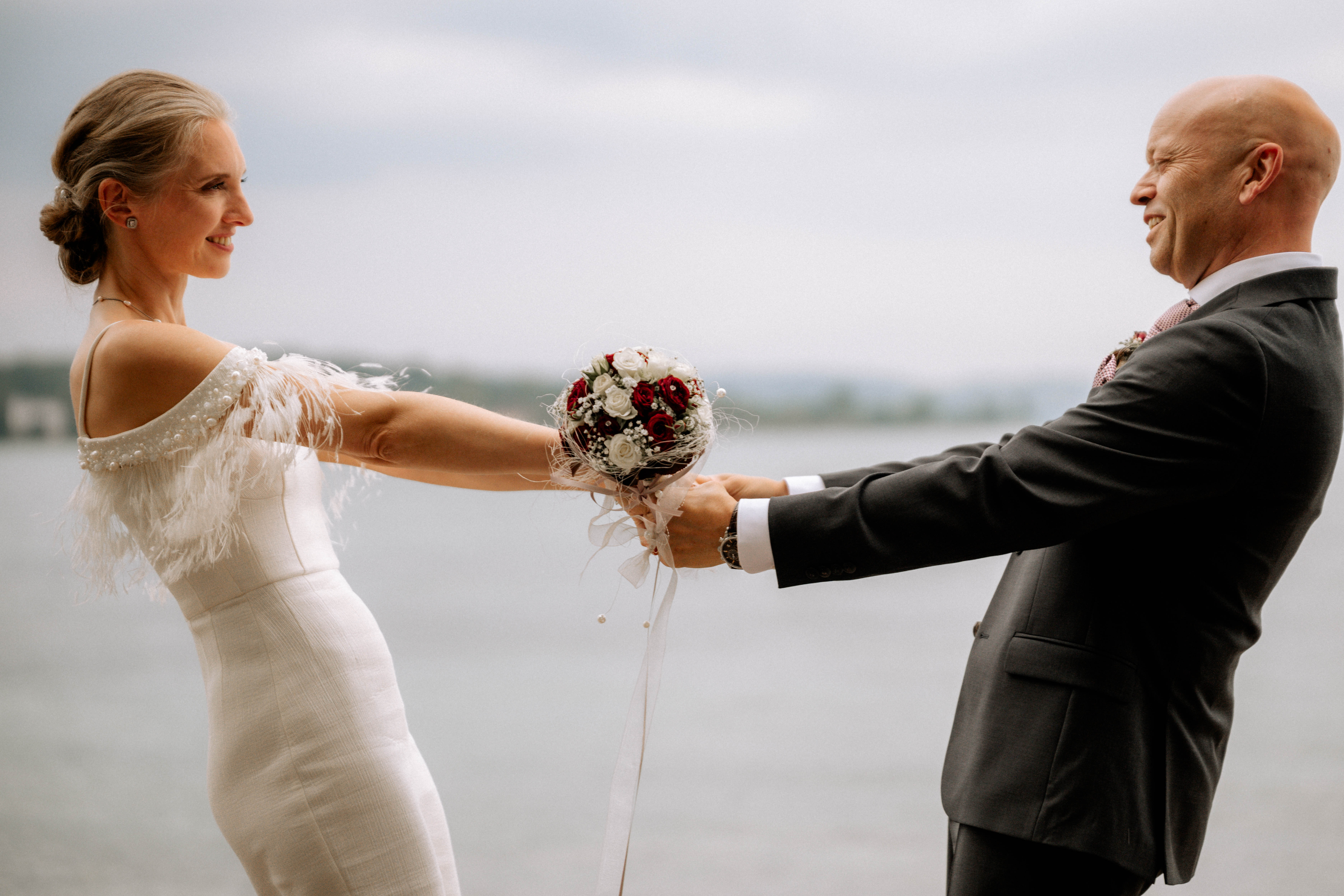 Brautpaar beim Paarshooting am Wasserstrand mit Blumenstrauss - Hochzeitsfotograf Pablo aus Thurgau