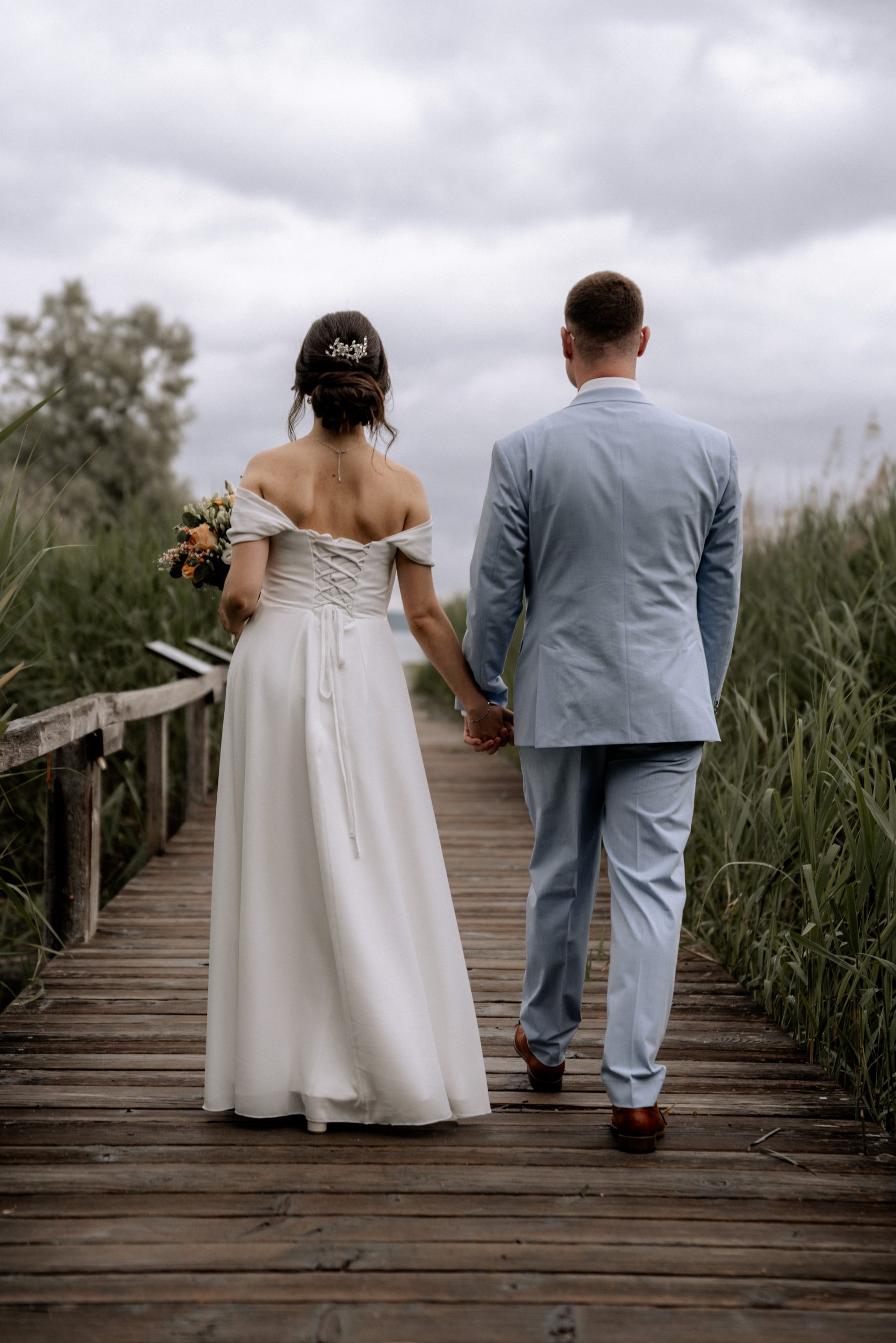Brautpaar Hand in Hand auf Holzsteg, Hochzeitsfotografie am See - Hochzeitsfotograf Pablo aus Thurgau